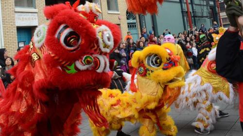 Colorful lion dancers parade through a city street.