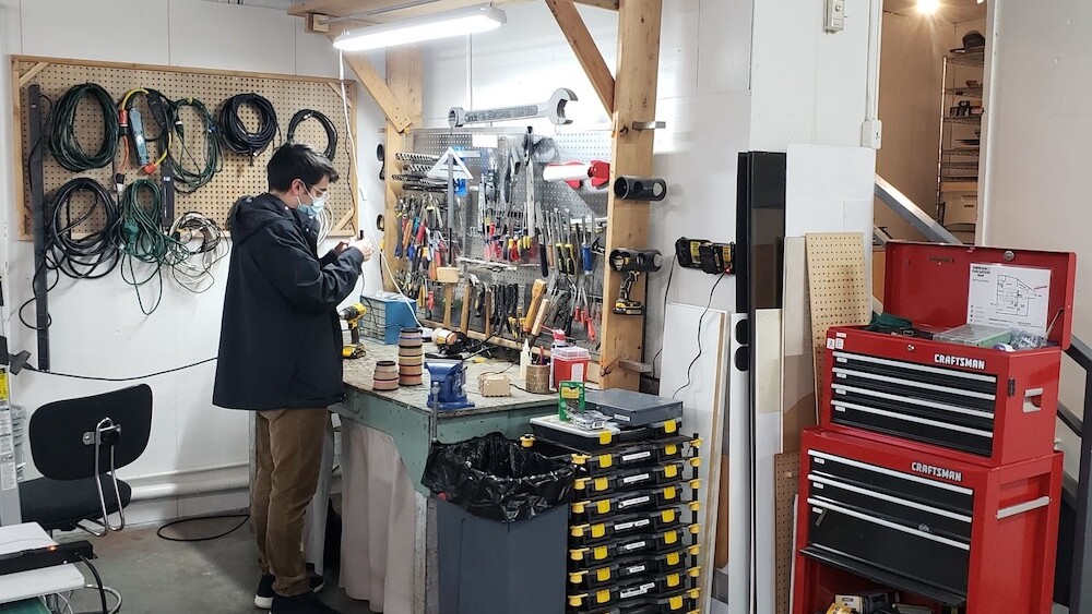 A man in a jacket peruses tools at a small workshop in the Seattle Maker space