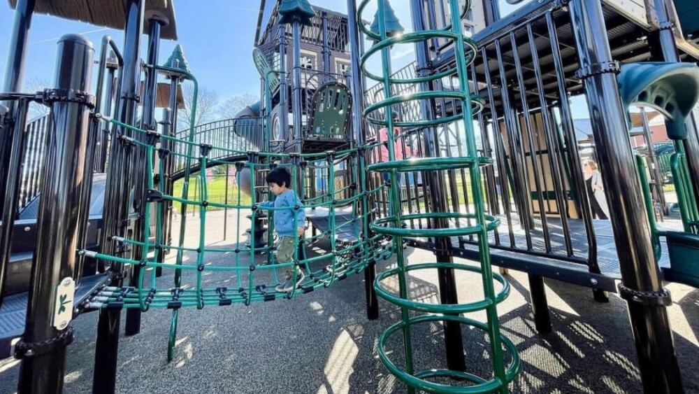 A child runs across a bridge on a play structure at Red Caboose Park.