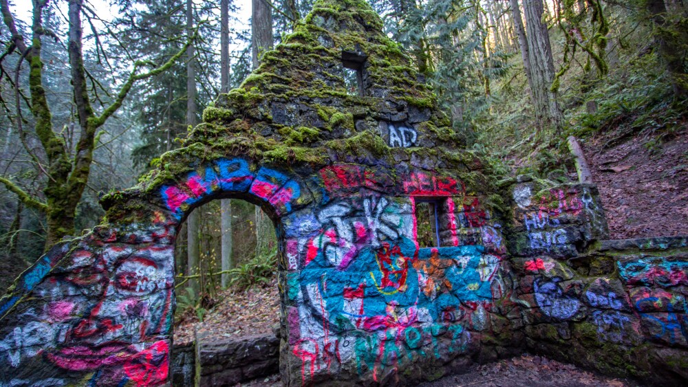 An old stone ruin covered in moss and spray paint