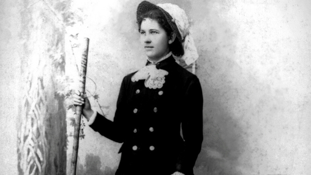 Researcher Rosa Smith Eigenmann holds a stick while staring off into the distance; she's wearing a petticoat and a hat.