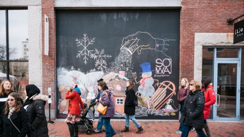 People walking in front of SoWa Boston chalkboard sign