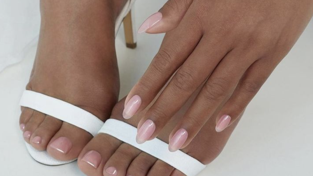 Close-up of Tanned feet in white heels with manicured light pink nails and toes