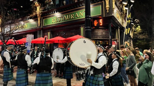 Bagpipe performers on the sidewalk in from of an Irish pub.