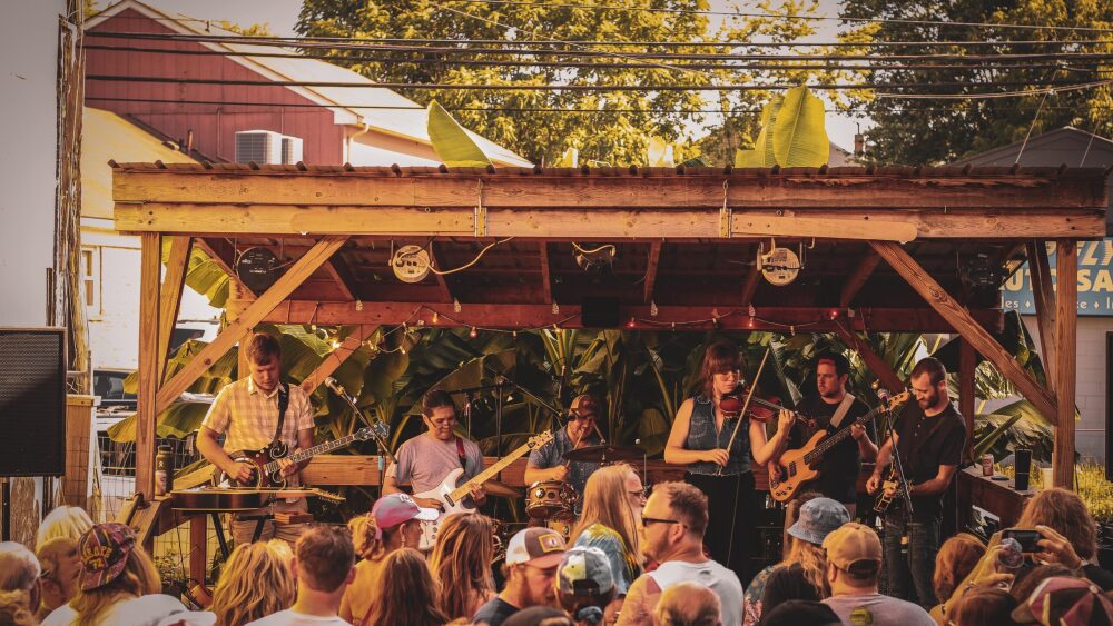 crowd standing in front of musicians playing on an outdoor stage