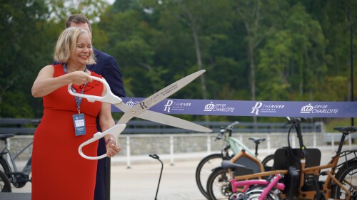 Mayor Vi Lyles holds a massive pair of scissors for a ribbon cutting ceremony.