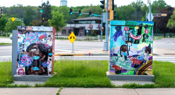 Two utility boxes wrapped in art by community members.