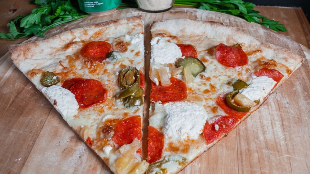 Two slices of pizza topped with pepperoni, ricotta, and jalapeños. 