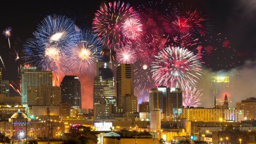 Multiple different bursts of fireworks light up the downtown Nashville skyline at night on the 4th of July.