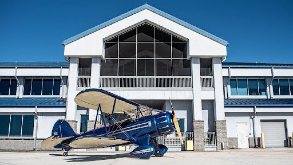 An old fashioned airplane in bright blue sits outside the airport.
