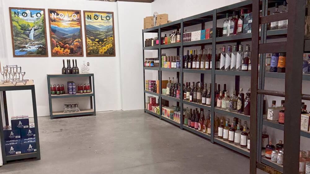 Shelves of bottles and cans with three NOLO posters at Atomic Furnishing.