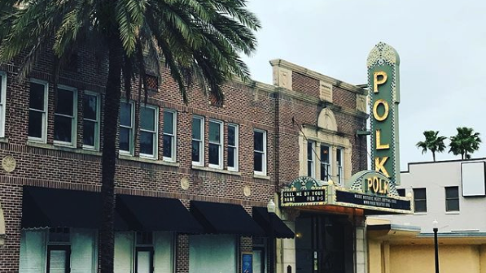 A historic theater building is shown with a palm tree in the foreground and a marquee that says "Polk" in the background.