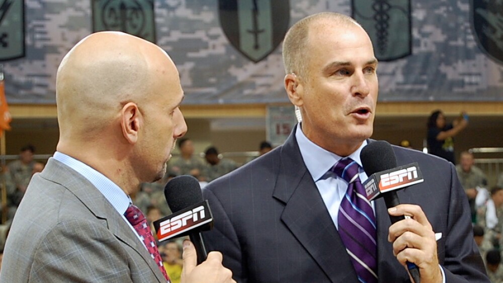 Jay Bilas holds an ESPN microphone with an on-air colleague on a basketball court.