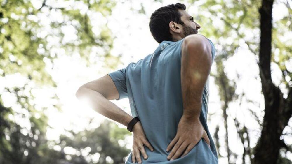 a man holds his lower back like he's in pain