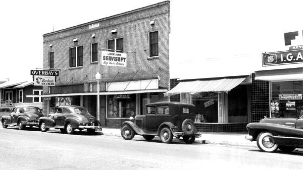 A black and white photo showing cars parked outside downtown storefronts in Lakeland in 1948.