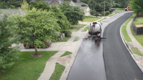 An aeriel view of a work truck applying a sealcoat treatment to a street in an Austin neighborhood.