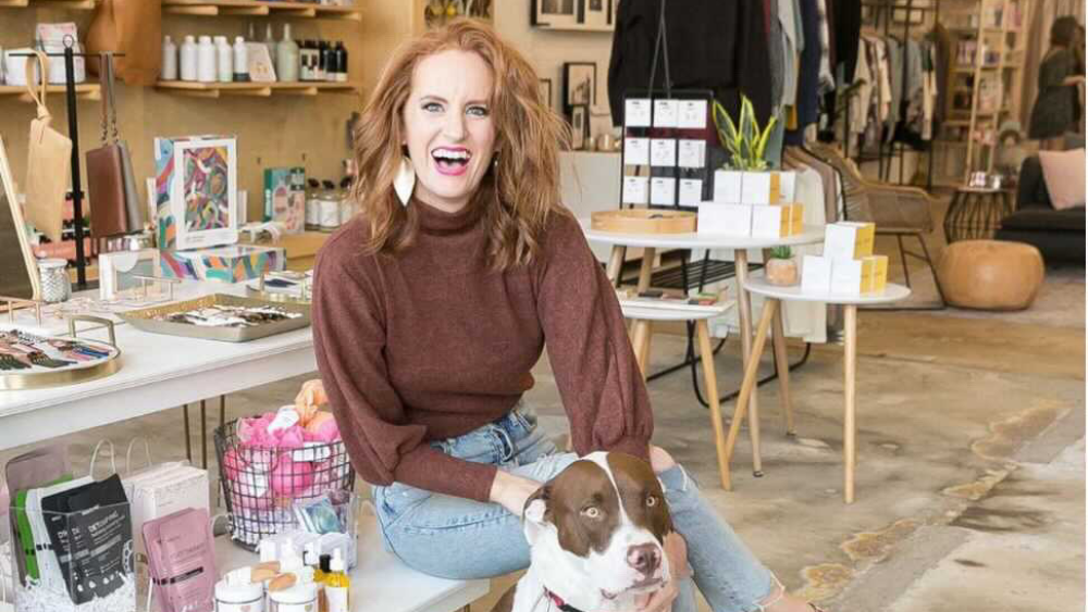 Emily Grey sitting in her store The Flourish Market with her dog.