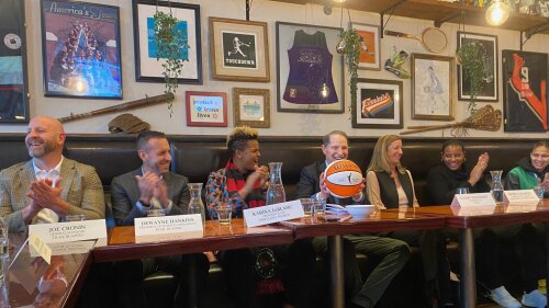 Seven people sit in booths behind a long line of tables at a sports pub.