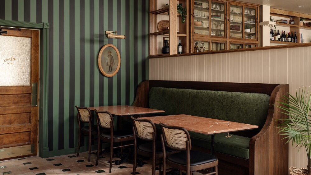 The entry to Poeta, with green striped walls and tiled floors. In the center of the image, a green lush booth is framed with tables and brown chairs.