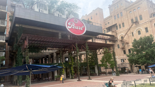 A massive structure covered in vines with a round red sign that reads "XXX Pearl."