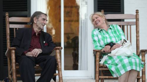 A man and woman sit on rocking chairs together.