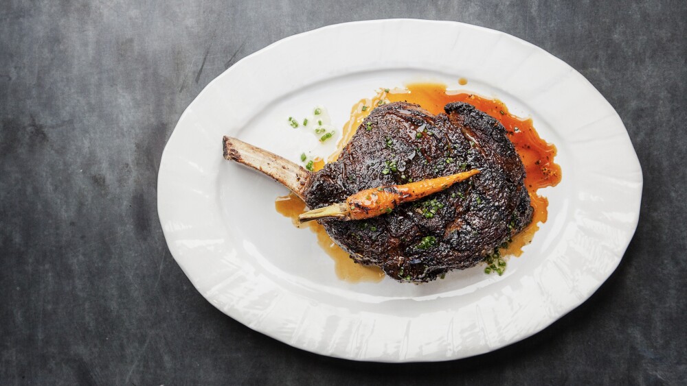 A cooked and seasoned steak is served on a plate.