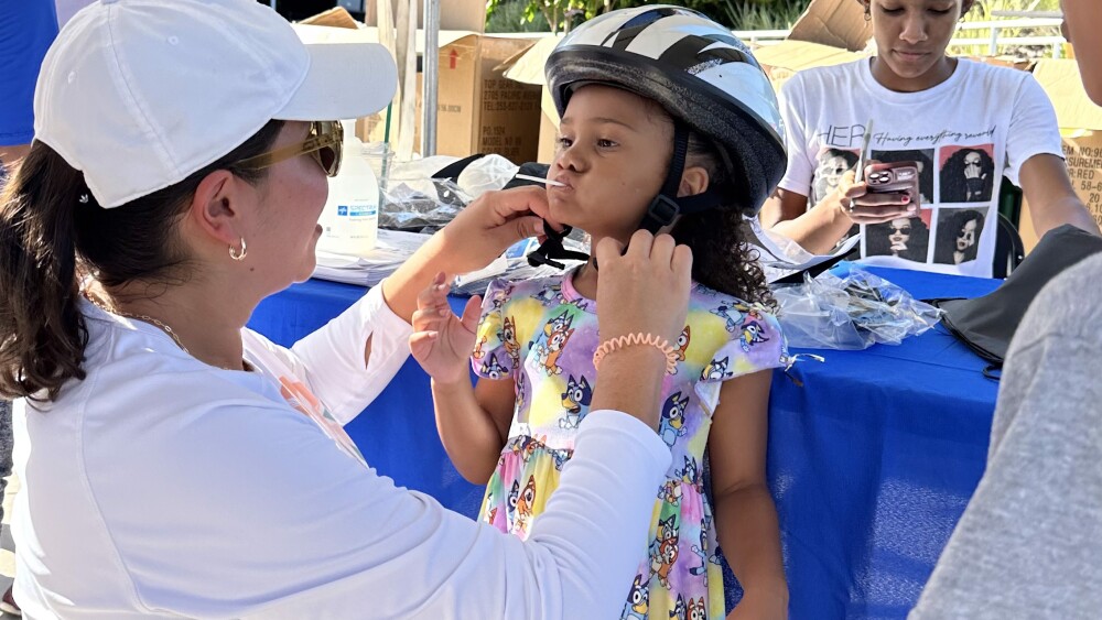 A woman putting a bike helmet on a child.