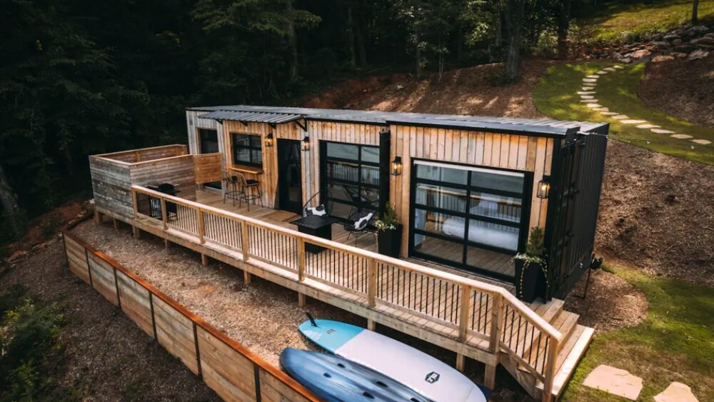 A home with a long deck and big windows made out of a shipping container.