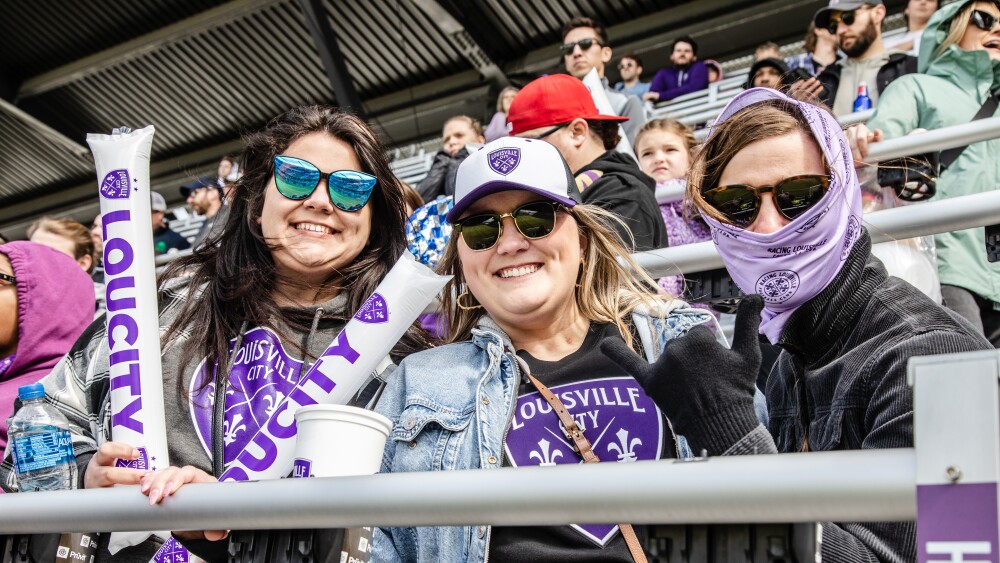 three louisville city fc fans cheer the team on from the stands