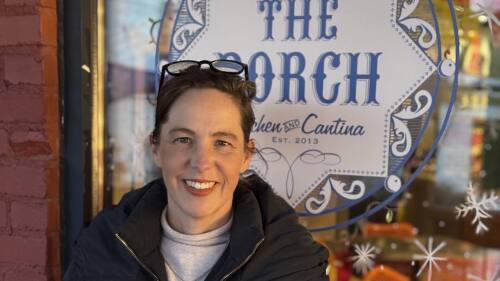 Person in coat standing in front of a store front.