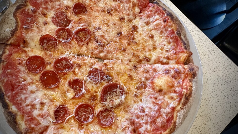 A cheese and pepperoni pizza served on a table.