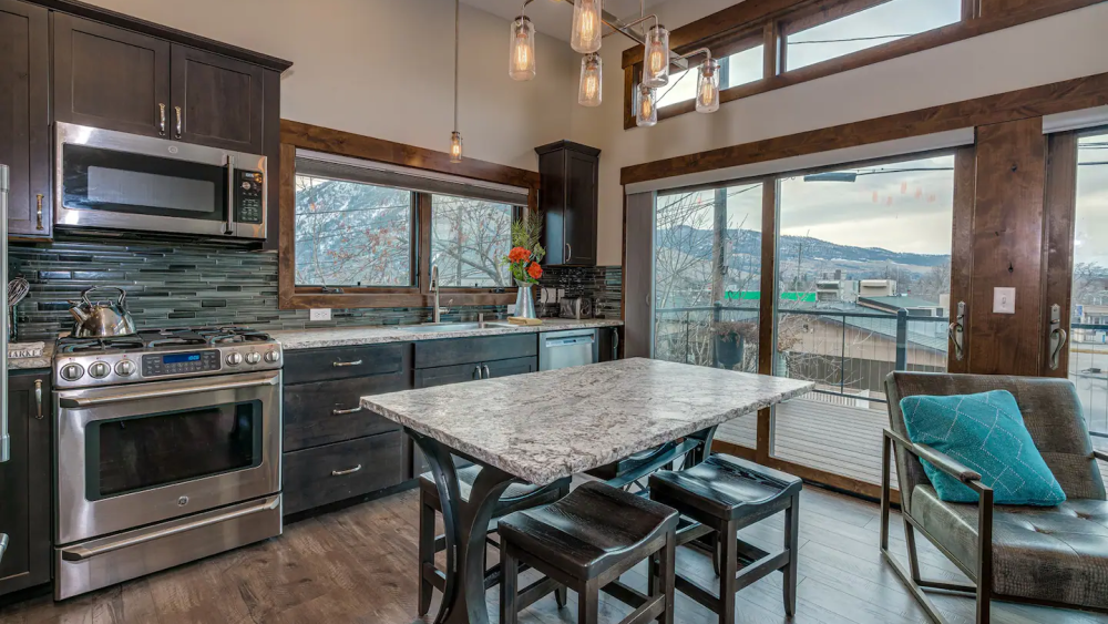 A photo of a kitchen with a window that has mountain views