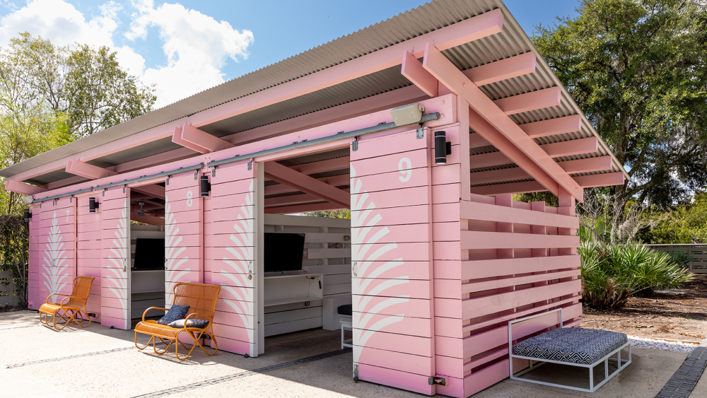 A pink poolside cabana with chairs at the entrance.