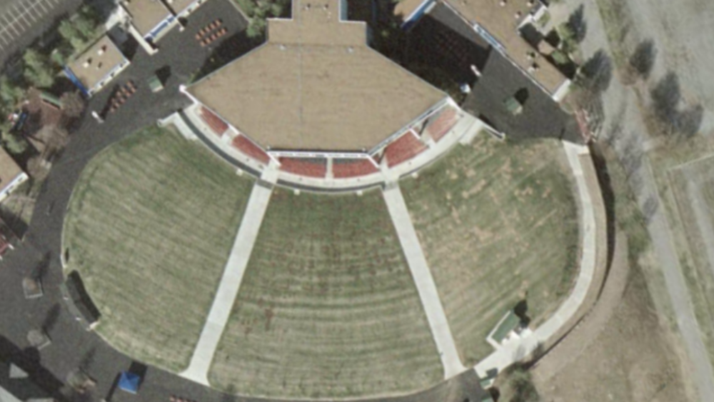 An aerial view of the top of the stage pavilion and three sections of grass seating.