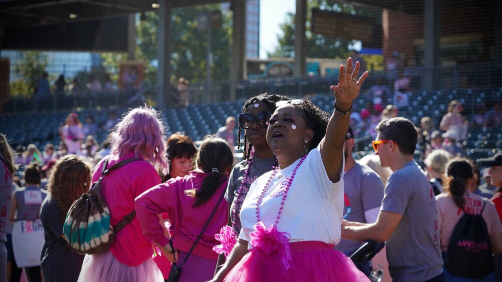 A crowd of people all dressed in pink walk during the Pink Cupcake Walk