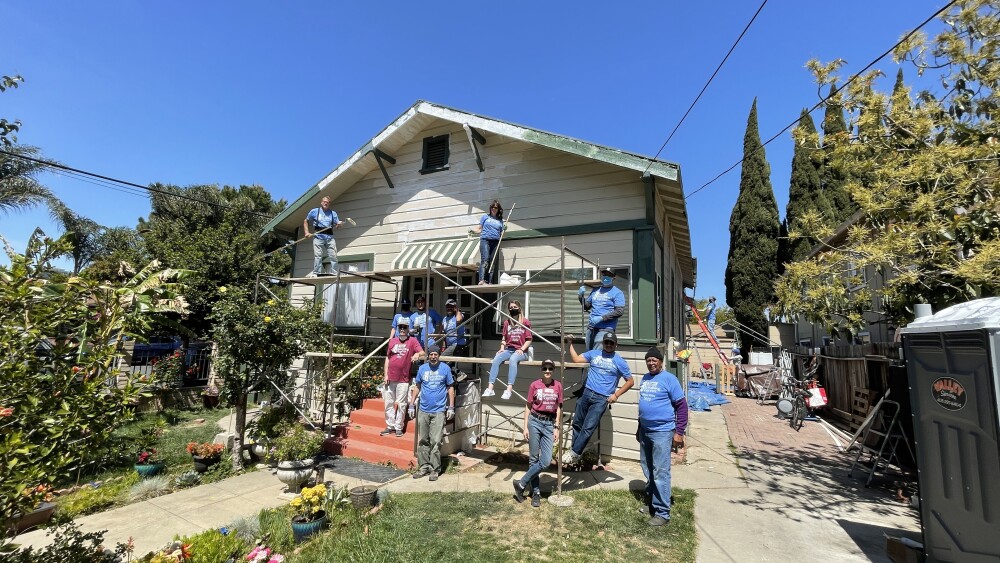 Several volunteers pose for a picture in front of a house. 