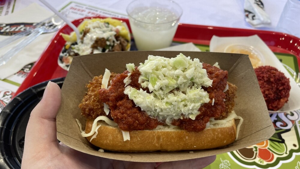 A sandwich with fried spaghetti, red sauce, and coleslaw.