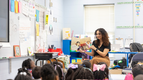 A volunteer reading to kids in a classroom.