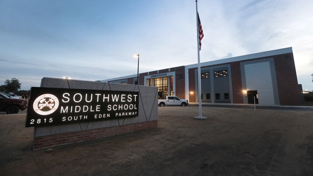 A new lit sign for Southwest Middle School sits in front of its newly built, two-story administrative building. A US flag pole sits a few feet away from the sign.