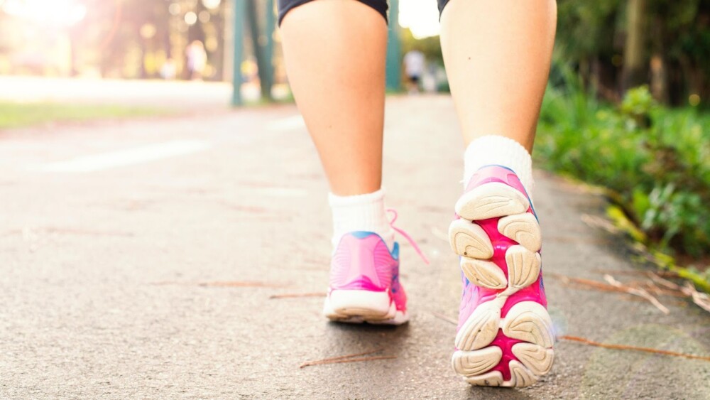 pink tennis shoes running on sidewalk