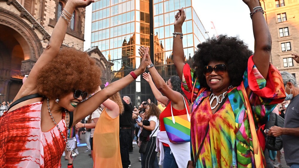 Two women cheering in colorful outfits at Copley Square Donna Summer disco party