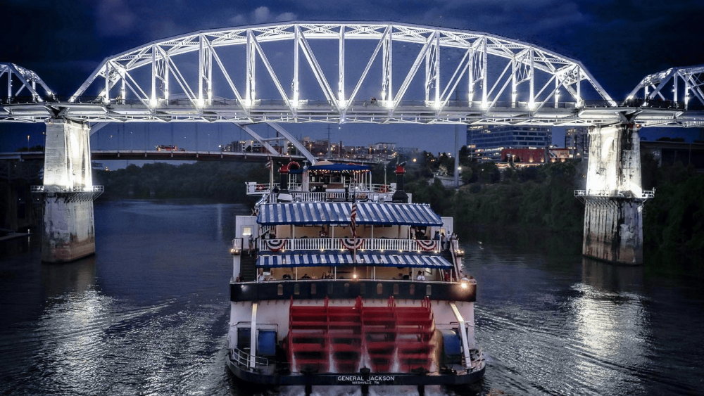 The General Jackson Showboat travels under the Pedestrian Bridge on the Cumberland River at night.