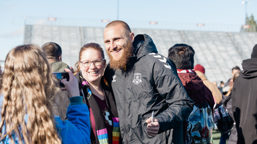 Republic FC goalkeeper Danny Vitiello takes smiling photograph with a fan.
