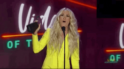 A gif of Carrie Underwood holding a CMT Award up to the crowd and whooping