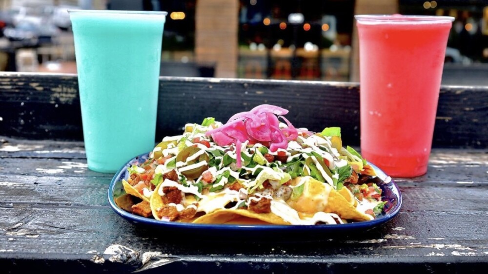 Nachos with a blue drink and a red drink.