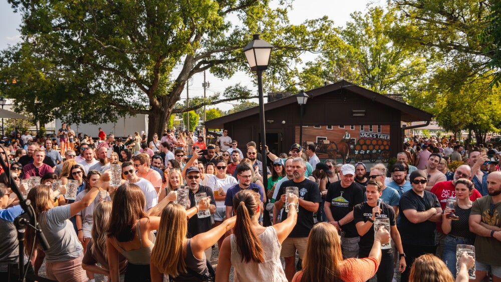 A group of women holding steins in a competition in front of a crowd.