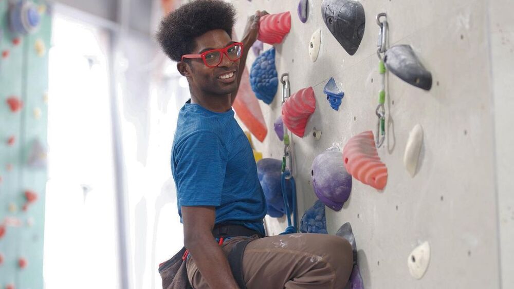 A man climbing up an indoor climbing wall. 