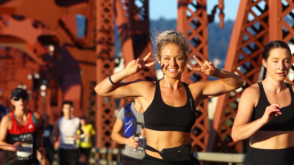 A runner poses with double peace signs as she crosses the Broadway Bridge during the Portland Marathon.