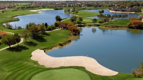 An aerial view of the Eaglebrooke Golf Course in Lakeland, FL. There is a green in the foreground and sand traps, water hazards, and trees in the background.