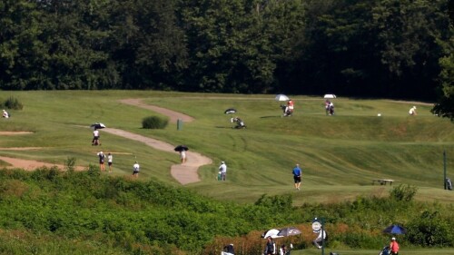 Golfers walking along a hilly golf course.